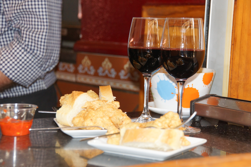 Tortilla de Patata mit einem Glas Rotwein und scharfer Soße